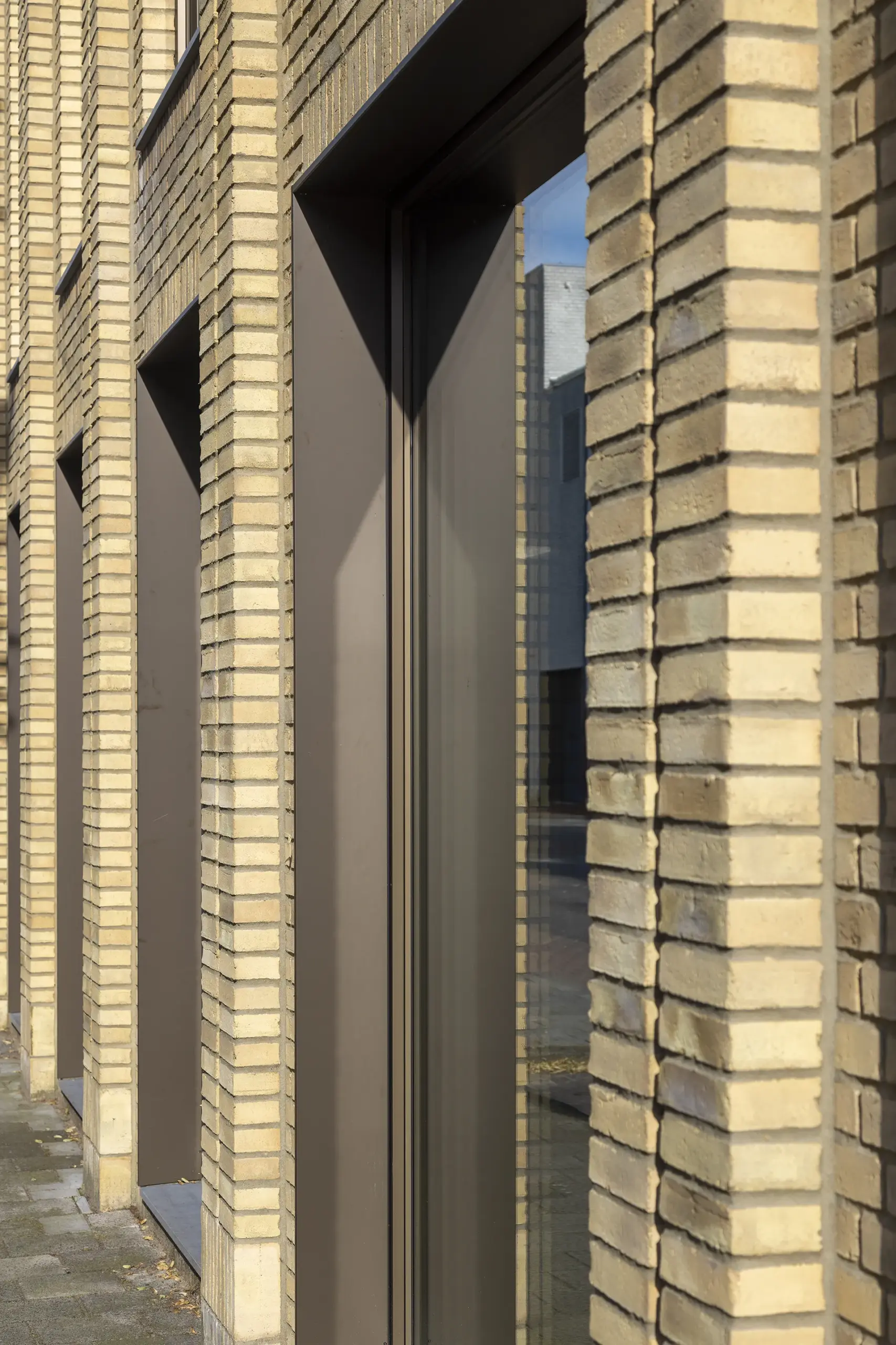 Gemetselde penanten van Petersen baksteen met daartussen geanodiseerde aluminium kozijnen in zetwerk kaders in dezelfde kleur.