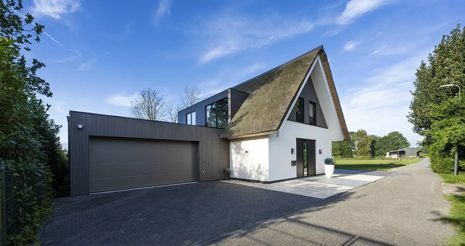 wit gestucte villa met rieten kap en aangebouwde garage in Sprang-Capelle.