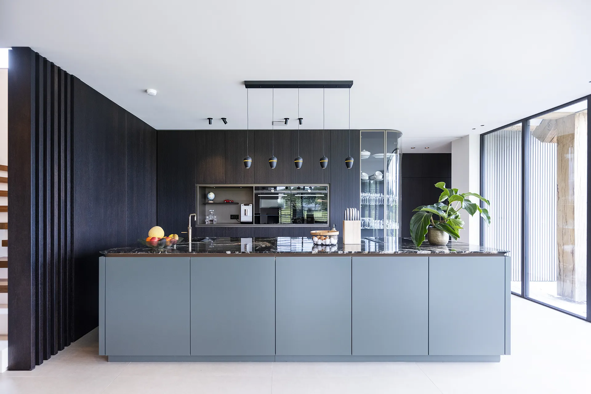 Moderne donkere keuken met glazen gebogen hoekkast.