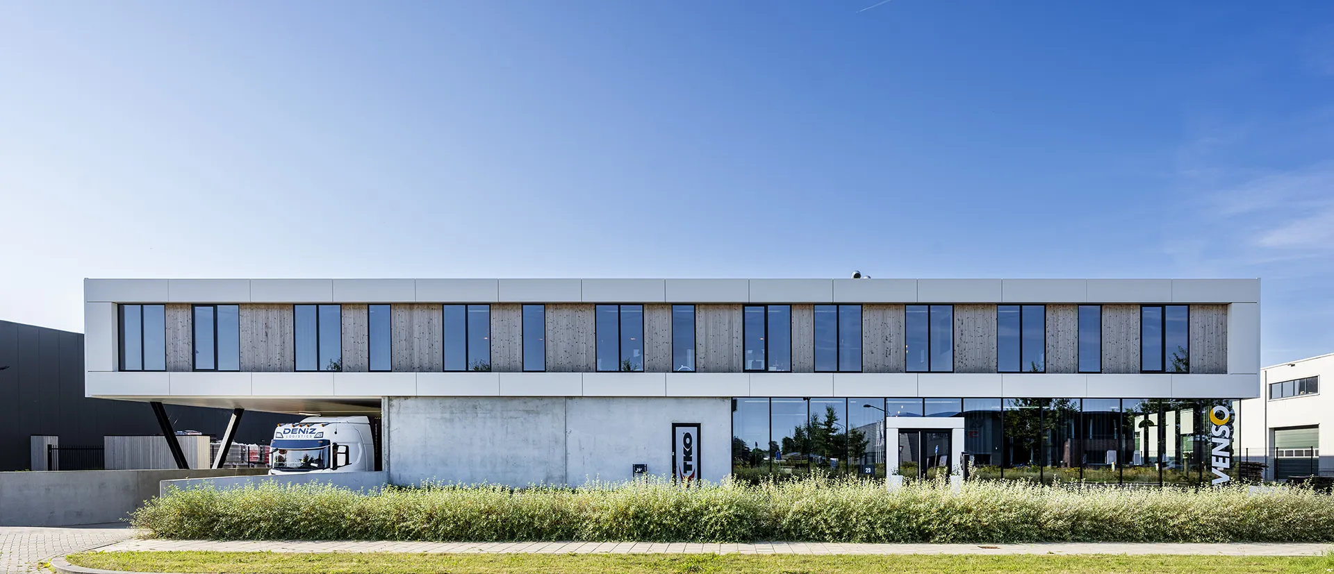 Kantoor in wit volume met gevelopeningen en houten invulling.
