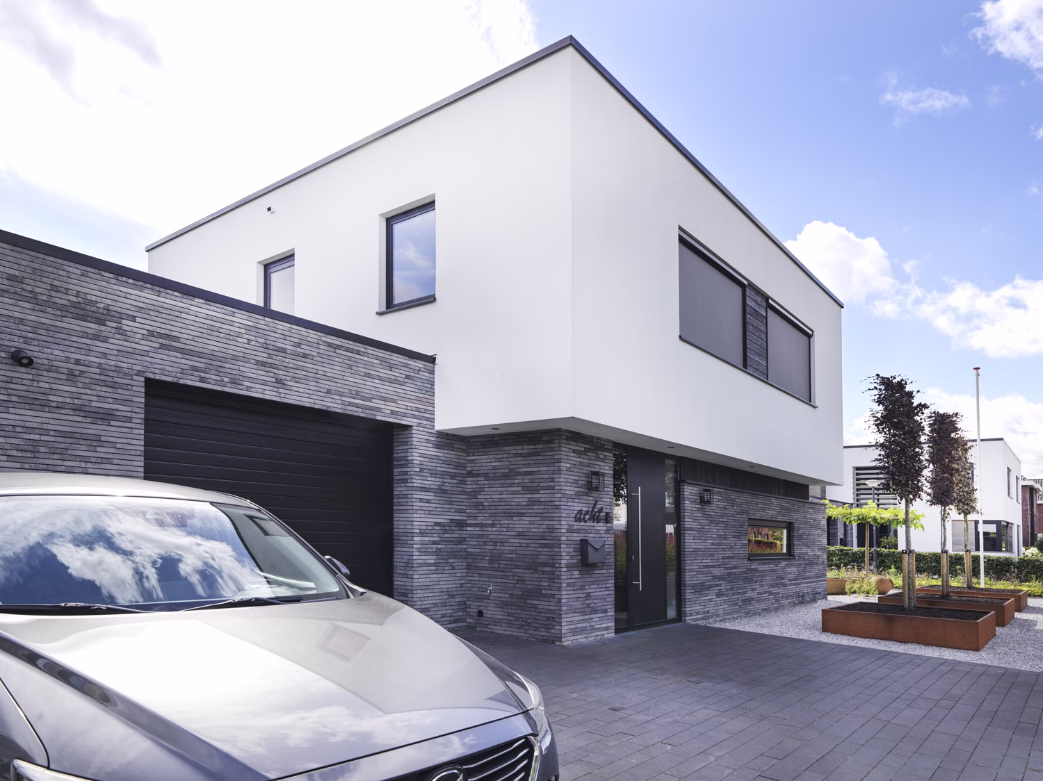 Moderne woning in Waspik met lange gevelstenen van GeoStylistix en wit gestucte verdieping.
