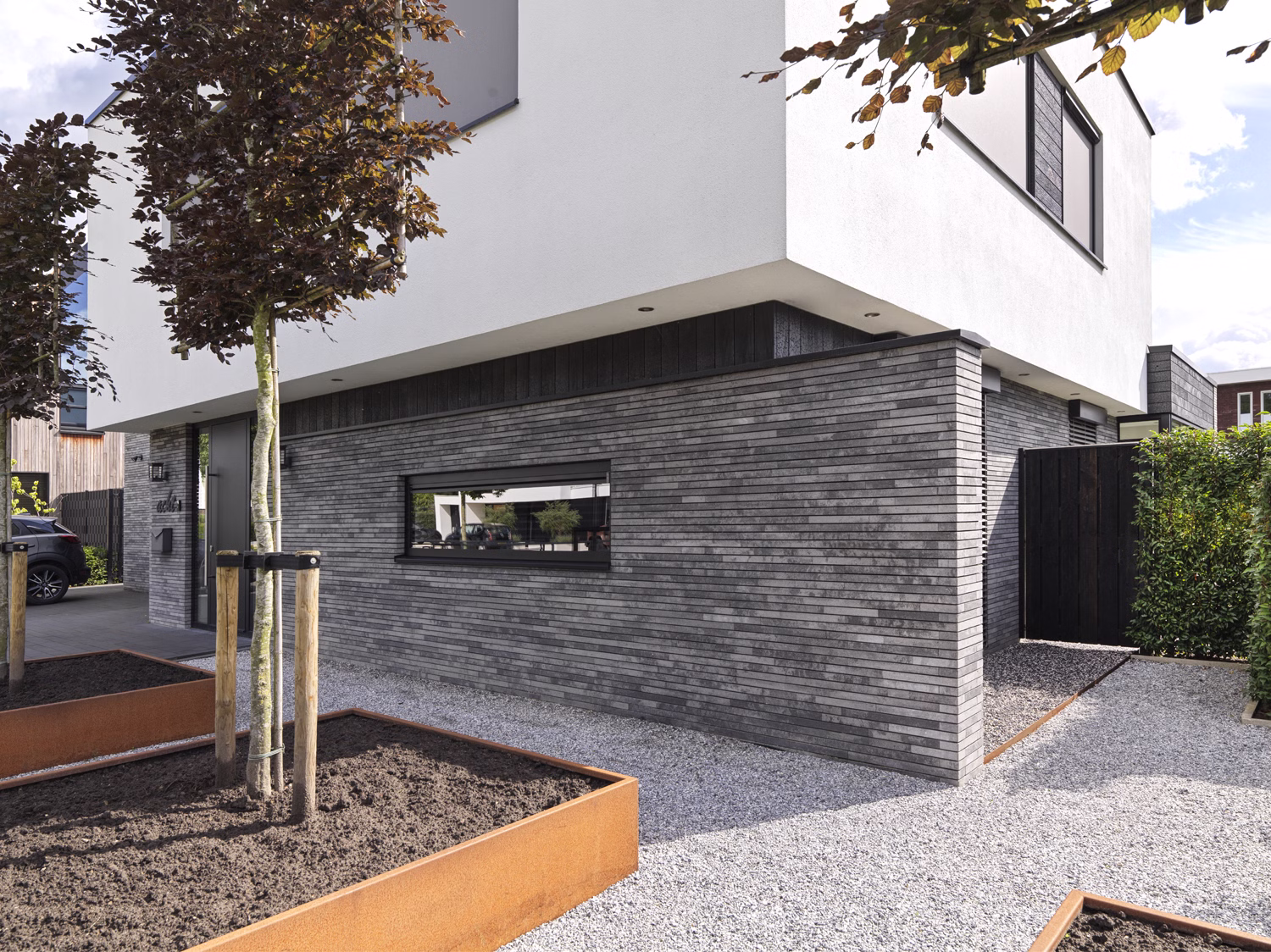 Gevel met Lange gevelstenen van GeoStylistix en uitkragende wit gestucte verdieping.