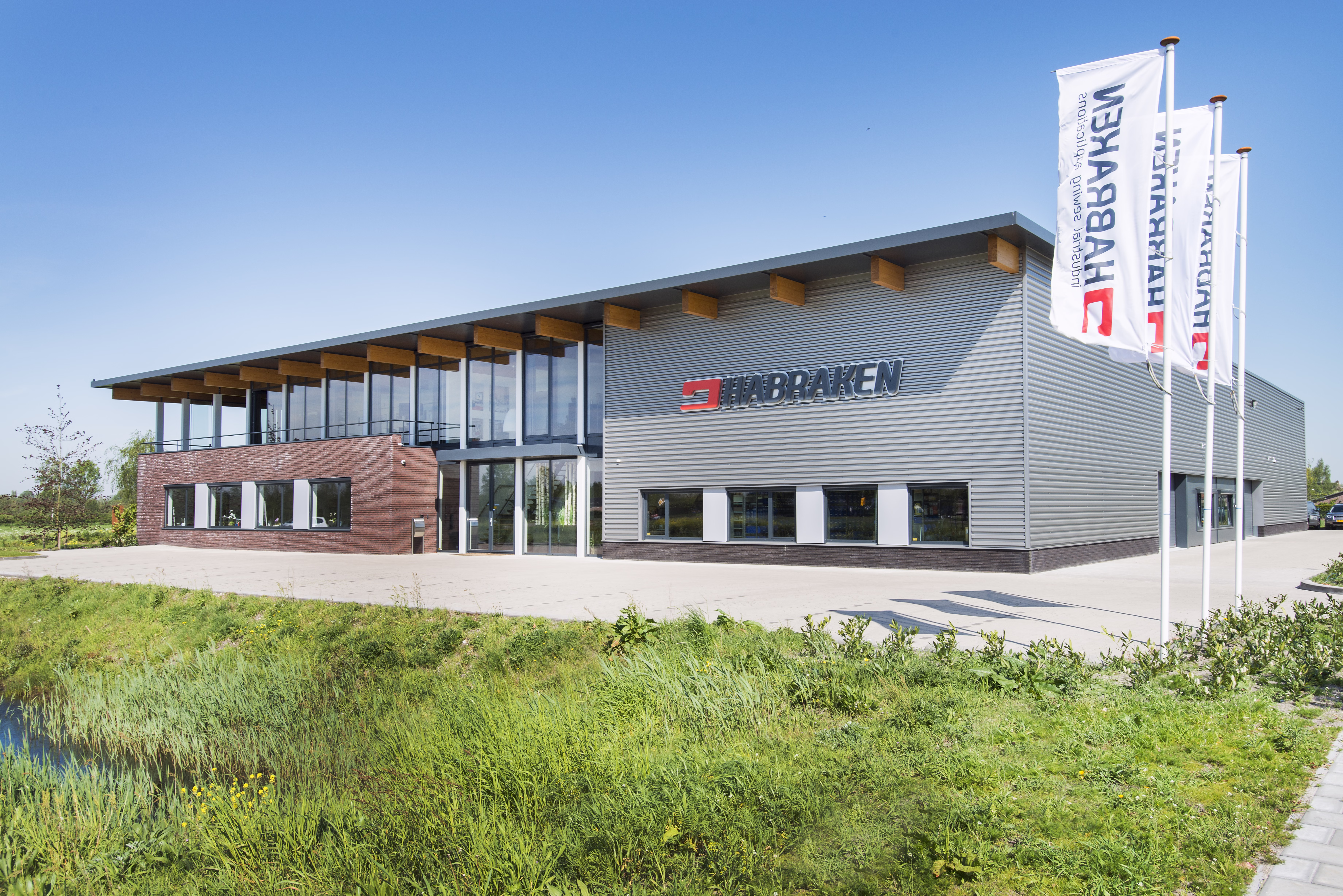 Entree van het bedrijfsgebouw met warme bakstenen gevel, houten constructie en ruime luifel.