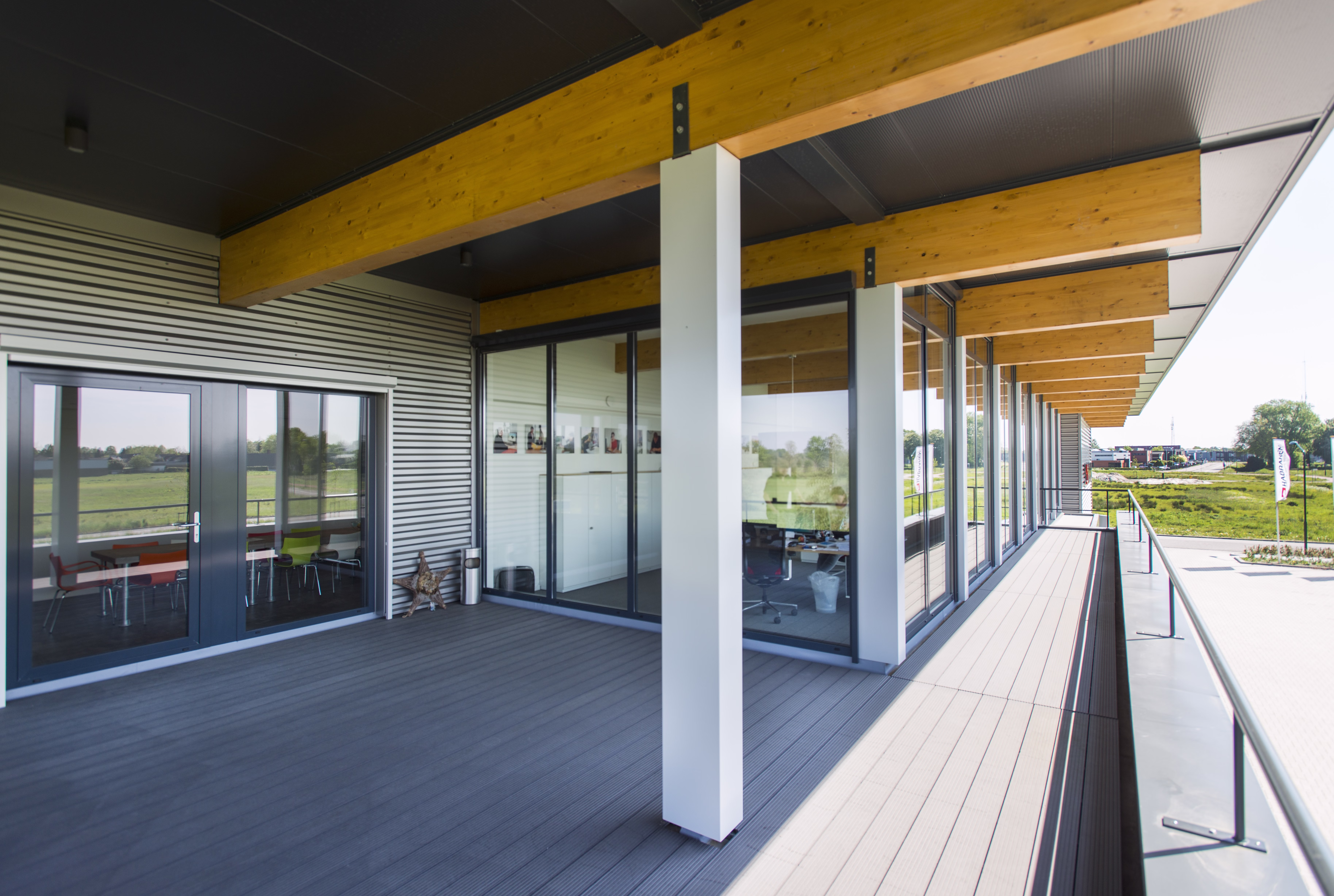 Schuin aanzicht van het bedrijfsgebouw met royale overstek, grote ramen en natuurlijke materialen.